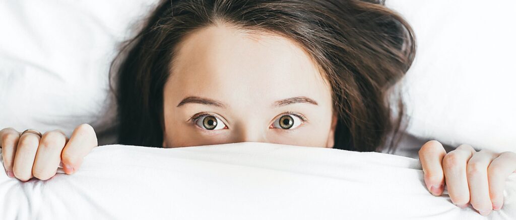 Woman hiding under covers with fear and no faith