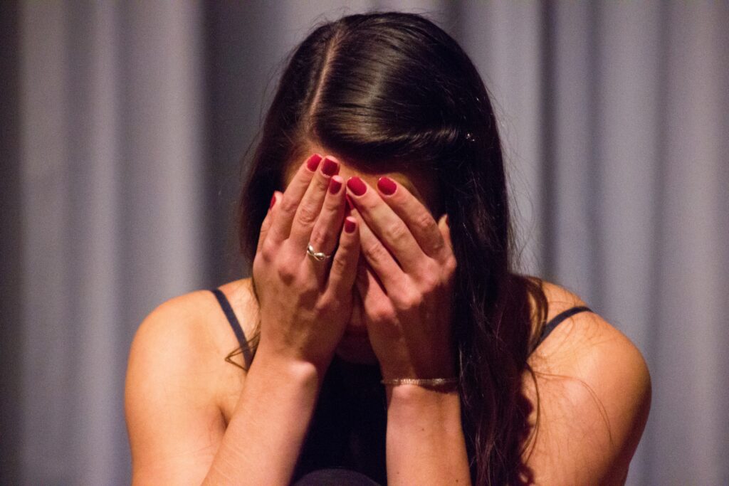 Woman with her head in her hands, symbolizing overcoming grief through comfort and hope in God’s Word.